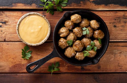 Traditional swedish meatballs in a fried pan with creamy sauce on old wooden table top view. High quality photo